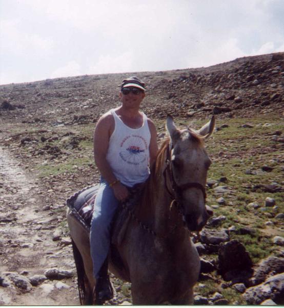 joe_st_martin_horeseback.jpg - Captain Joe on horseback in St. Martin. No, its not a donkey but an Andalasian, which is a very spririted, small horse from Spain.ANDALUSIAN:  Ancient breed from Portugal and Spain, where all exportation of breeding stock was once prohibited,  Classic horse of tthe Caballeros and Conquistadores, Andalusions whave provided foundation bloodstock for many other breeds, including the Lippizanners.